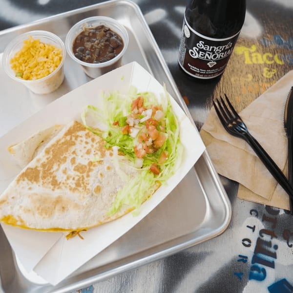 Quesadilla with lettuce and pico de gallo, rice, beans, and a Sangria Señorial on a tray.