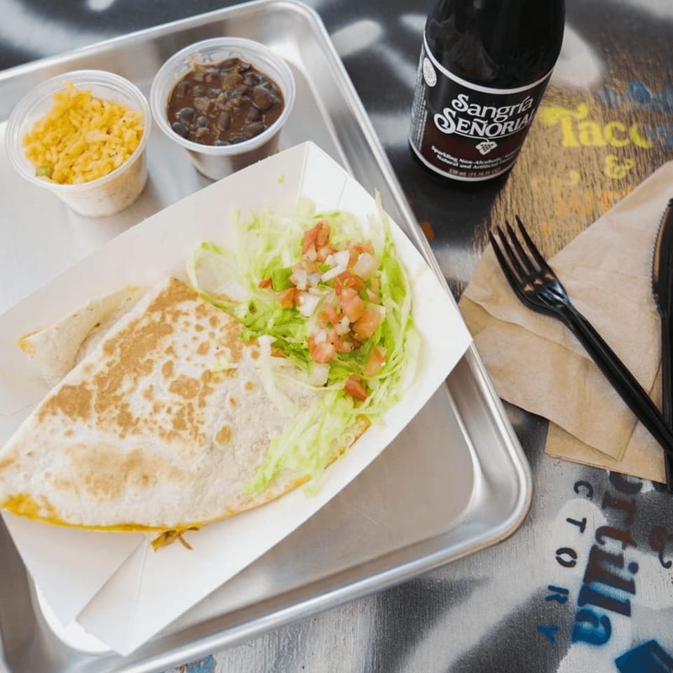 Quesadilla with lettuce and pico de gallo, rice, beans, and a Sangria Señorial on a tray.