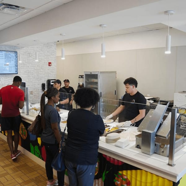 Customers ordering Mexican food from staff at the Tacos and Tortilla Factory counter.