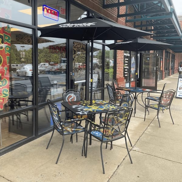 Outdoor seating area of Tacos and Tortilla Factory with colorful tables and chairs under black umbrellas.