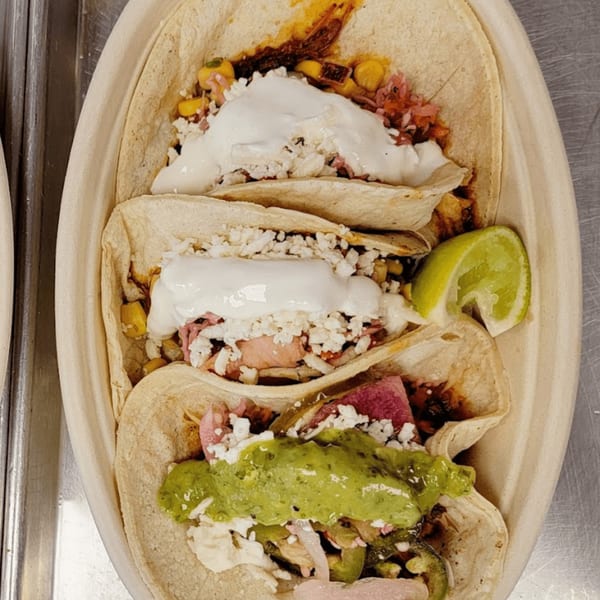 Three vibrant Tacos and Tortilla Factory tacos with various toppings and a lime wedge.