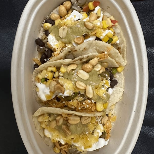 Three Tacos and Tortilla Factory tacos with peanuts, corn, black beans, and green sauce in a bowl.